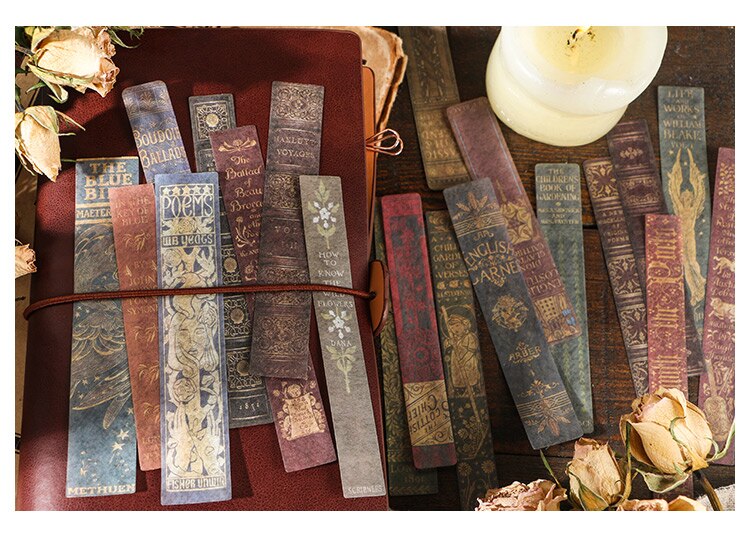 Long vintage book-spine stickers in muted red, brown and green arranged over a journal, with ornate printed lettering.
