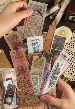 Long colourful ticket stickers held above a paper collage, with faded numbers and printed text visible along the strips.