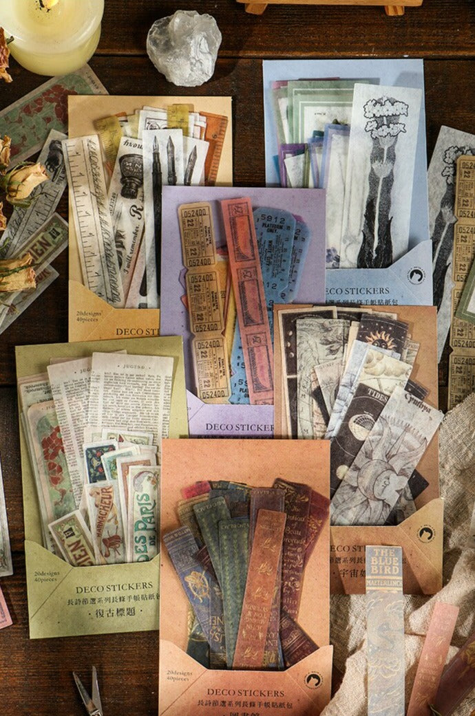 A vertical stationery display shows several vintage sticker packs surrounded by paper pieces, a candle and decorative objects.
