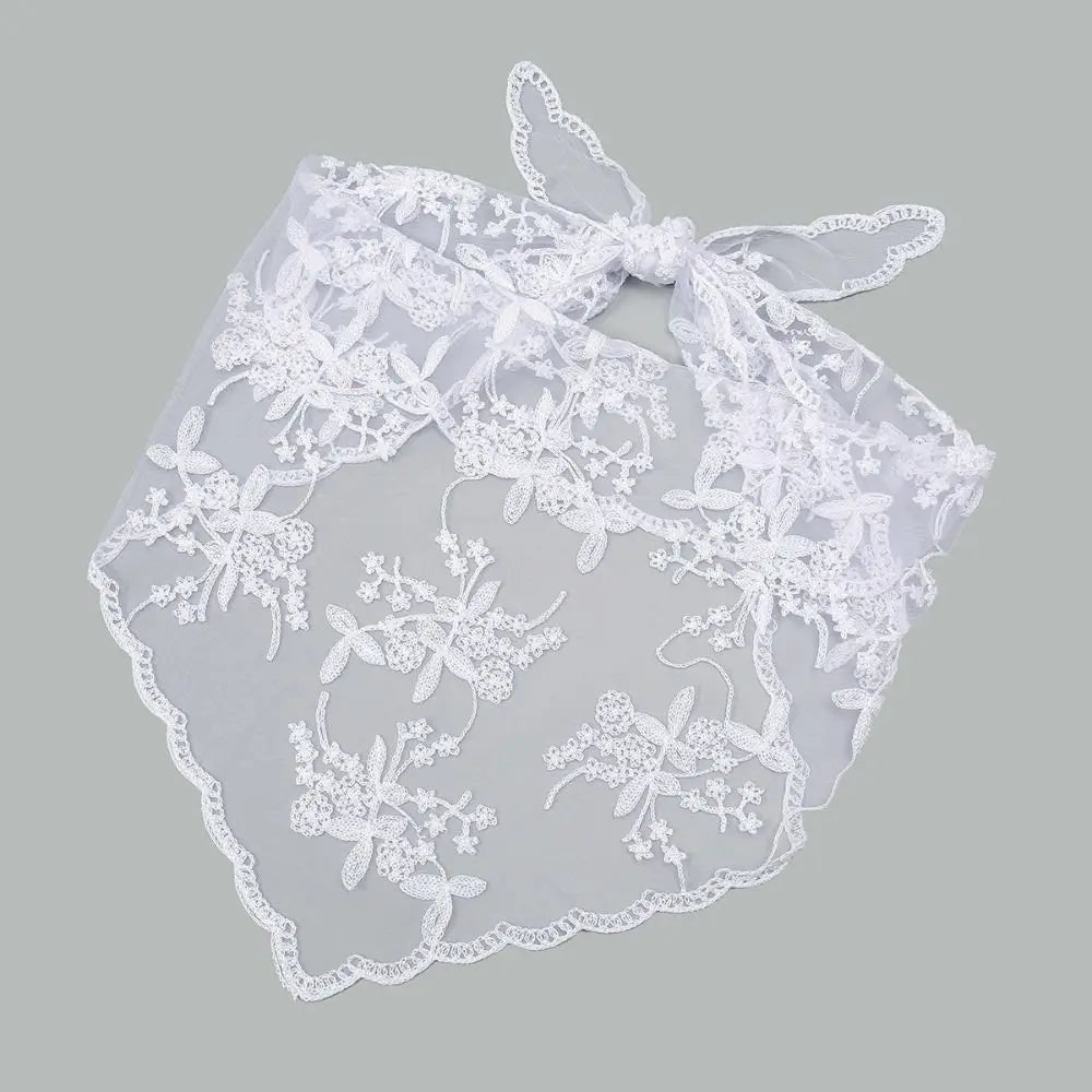 White floral lace bandana tied in a bow and laid flat on a grey background. The triangular floral panel and scalloped edges are visible below the tied ends.