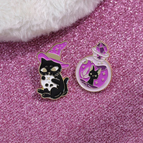 Witch-hat cat and potion-bottle cat enamel pins arranged together on a sparkling pink-purple background.