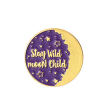 Purple circular enamel pin reading Stay Wild Moon Child, decorated with small stars and a broad gold-tone crescent.