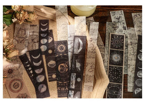 Long celestial sticker strips with moons, orbit diagrams and dark astronomical illustrations spread across a wooden surface.