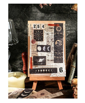 A small easel holds a journal-style collage of moon phases, stars, numbers and long celestial sticker strips.