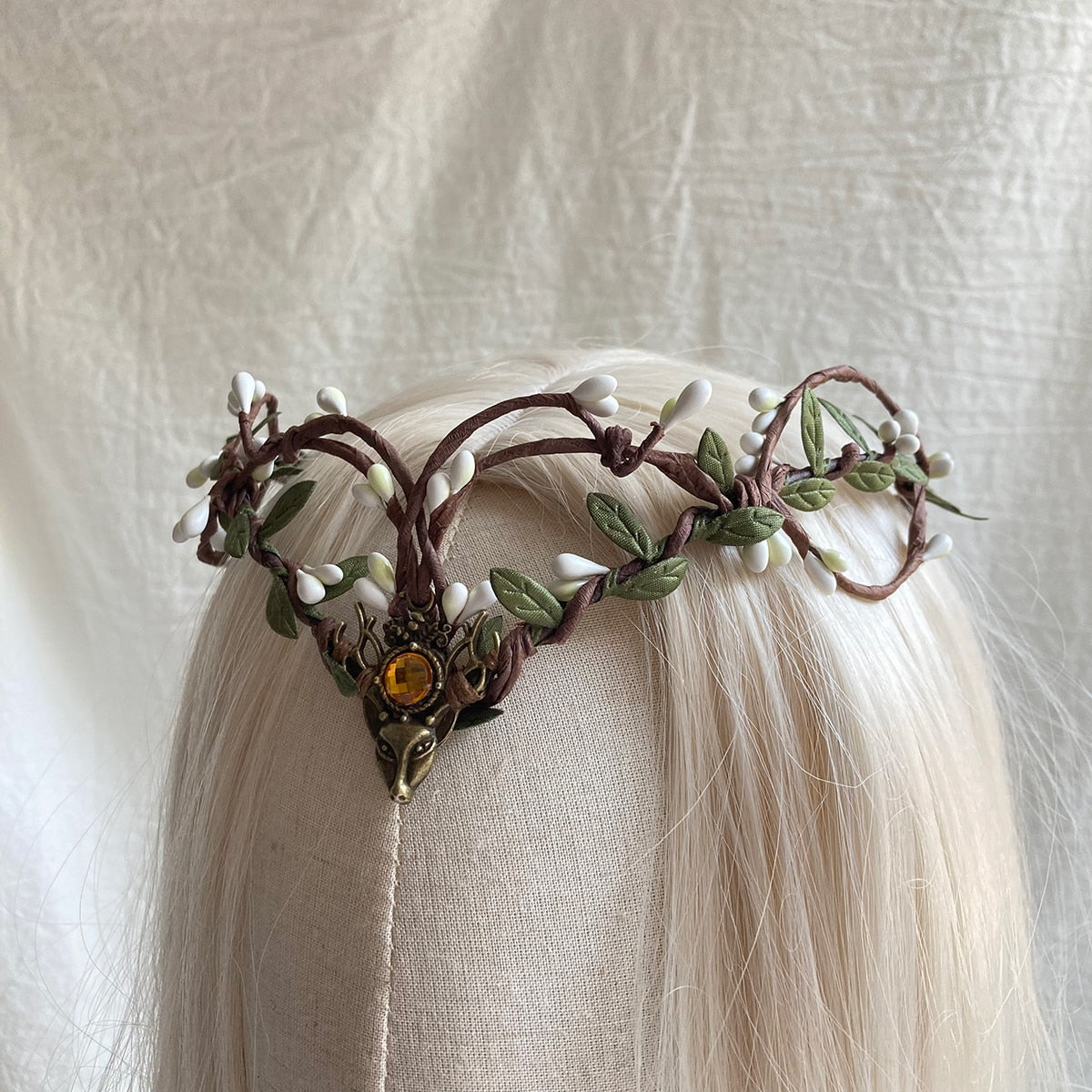 Brown looping-branch tiara with pale buds and an amber-coloured deer-head centre, shown on pale hair.