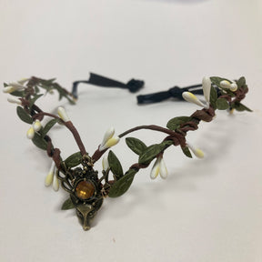 Brown branch-style tiara with white buds and green leaves framing an amber-coloured central accent.