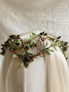 Black-centred woodland tiara shown at an angle on pale hair, with small dark buds and green leaves around the band.