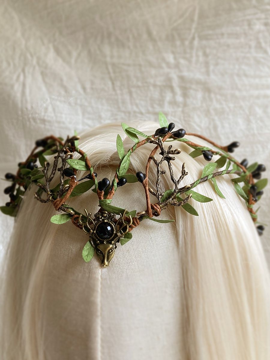 Black-centred woodland tiara shown at an angle on pale hair, with small dark buds and green leaves around the band.
