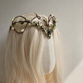 A side view of the black-centred woodland tiara shows its looping brown branches, pale buds and green leaf accents.