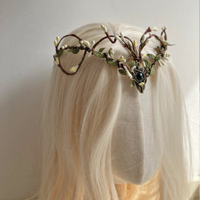 Dark-centred brown branch tiara with pale buds and small green leaves, photographed from the side on pale hair.