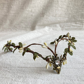 Elf-inspired tiara with brown branching bands, pale buds and leaves around a clear jewel-like deer-head centre.