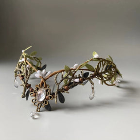 Antiqued gold-tone leafy tiara with pale buds and a clear oval centre ornament ending in a hanging teardrop.