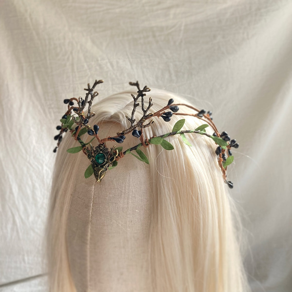 Angled view of the green-centred berry-and-antler tiara on pale hair, showing the height of its branching details.
