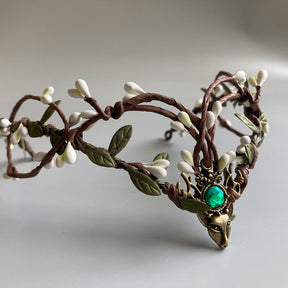 Brown branching tiara with pale buds, green leaves and a bright green round accent in its deer-head centrepiece.