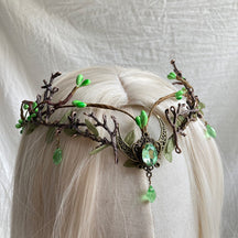 Light green crescent-and-antler tiara displayed on pale hair, with a matching green drop hanging over the centre part.