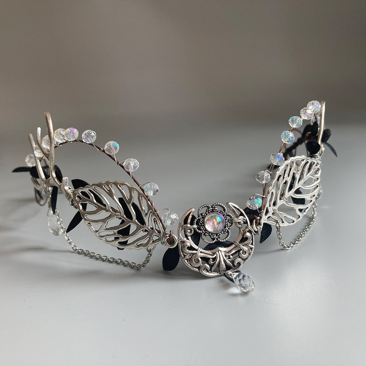 Silver-tone leaf tiara with clear faceted beads, draped chains and a central crescent ornament with a hanging clear drop.