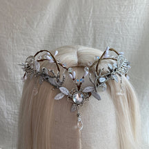 Silver-tone leaf headpiece with a round clear centre, small pale buds and a hanging teardrop, displayed on pale hair.