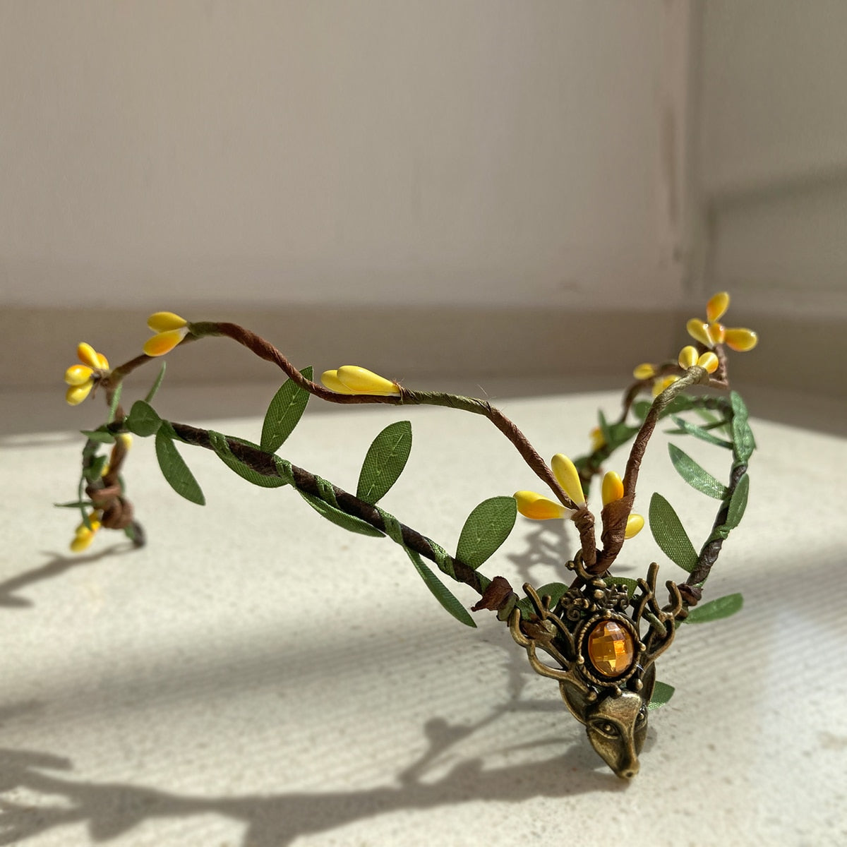 Leafy woodland tiara with yellow buds and an amber-coloured centre accent, photographed in sunlight.