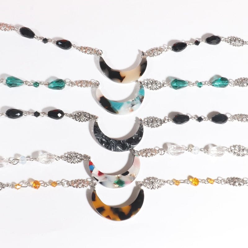 Five acrylic crescent headdresses arranged in rows, showing beige tortoiseshell, teal marble, black marble, colourful flecks and amber tortoiseshell designs with coordinating beads.