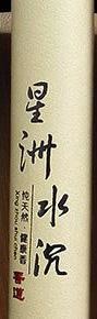 Detail of the pale agarwood incense tube with vertical black Chinese lettering.
