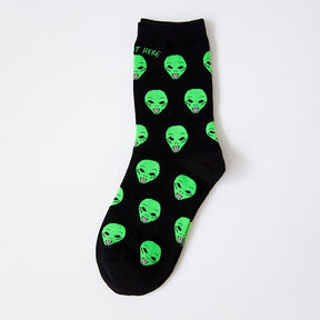 Black crew-style sock with repeated green alien faces sticking out their tongues, shown flat with its heel and toe visible.
