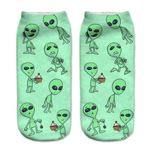 Green socks with a repeating print of small aliens in different poses, including characters holding cupcakes.
