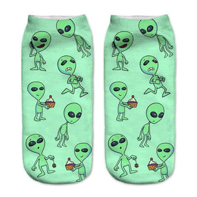 Green socks with a repeating print of small aliens in different poses, including characters holding cupcakes.
