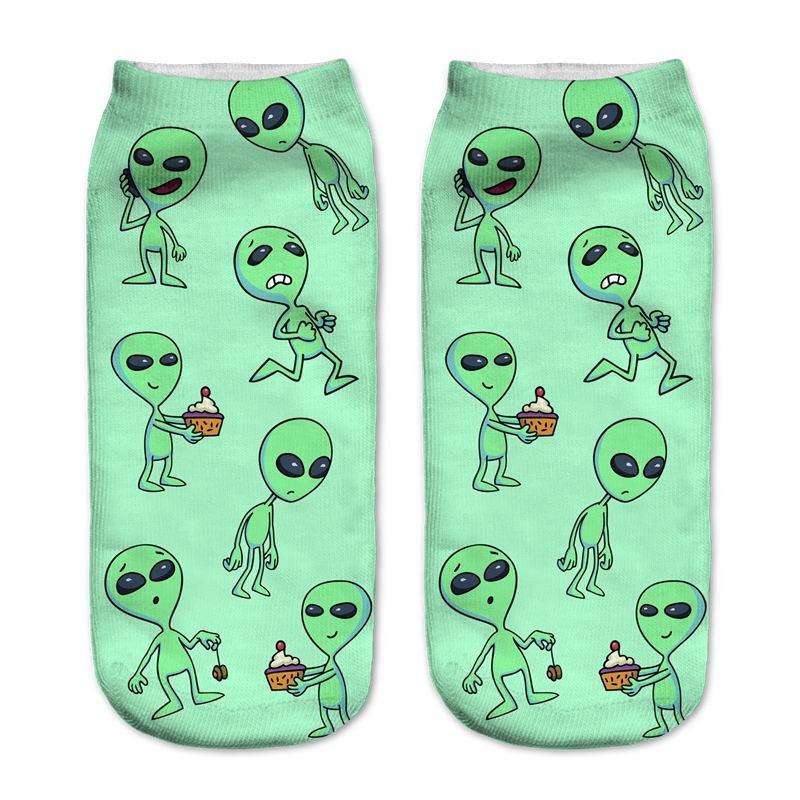 Green socks with a repeating print of small aliens in different poses, including characters holding cupcakes.