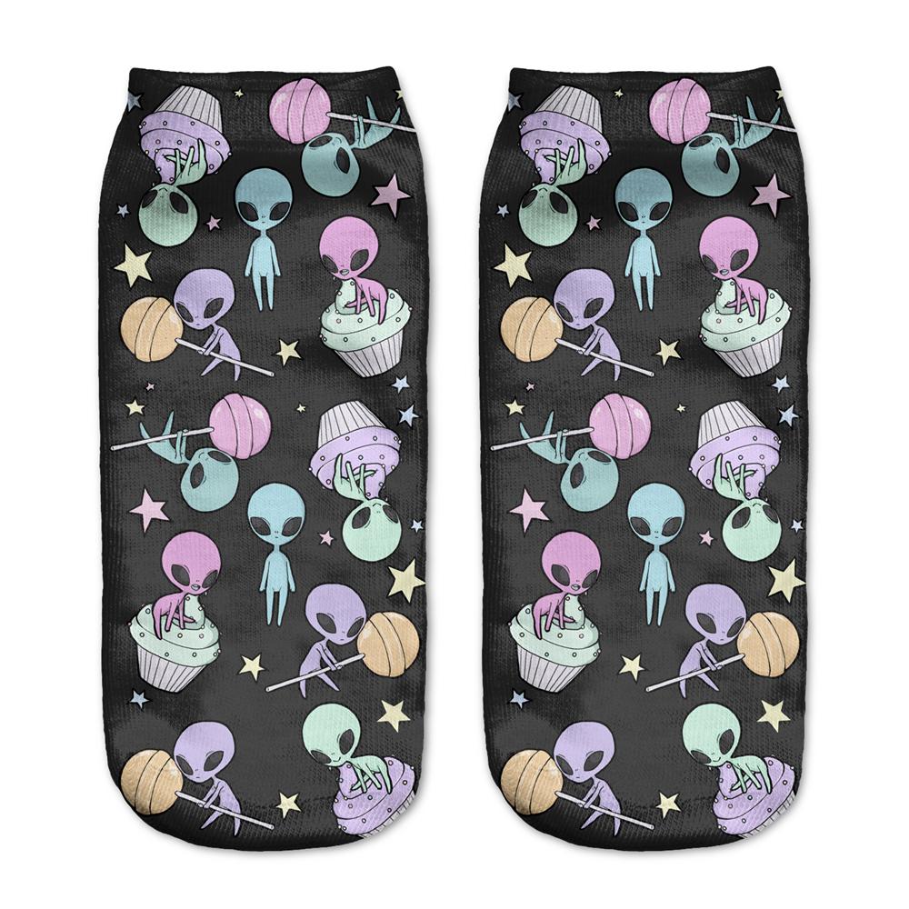 Black alien socks with pastel aliens, flying saucers, planets and little stars, displayed as a matching pair on a pale background.