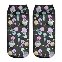 Black alien socks with pastel aliens, flying saucers, planets and little stars, displayed as a matching pair on a pale background.