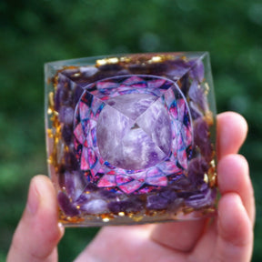 Top view through the clear amethyst lotus pyramid, showing the round purple sphere and layered pink-purple flower design beneath it.
