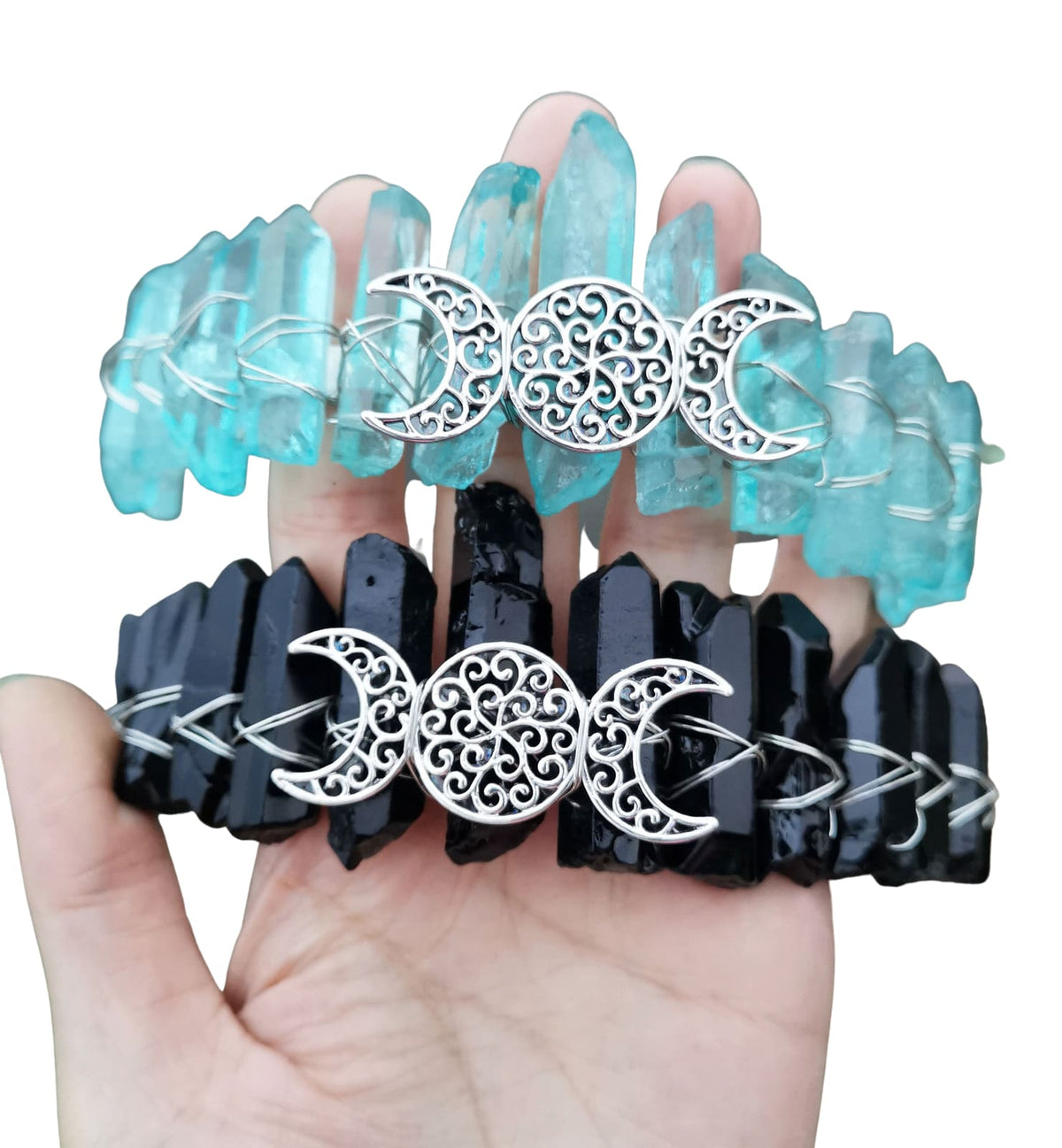 Aqua and black crystal crowns paired on white, showing matching silver-tone triple moon emblems and contrasting crystal points.