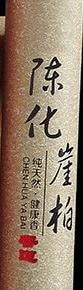 Close view of the brown arborvitae incense tube, with vertical Chinese lettering and a red seal near the bottom.