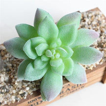 Green artificial succulent with long pointed leaves forming a layered rosette.