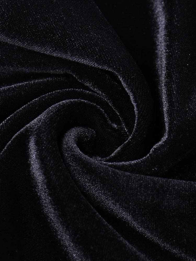 Close-up of black velour arranged in a swirl, showing the short pile and changing sheen of the dress fabric.