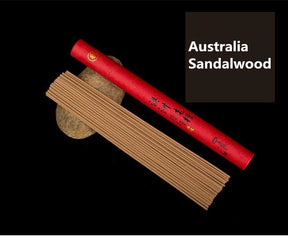 Australian sandalwood incense sticks arranged next to a red paper tube on a black background.