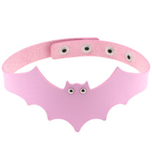 Pink faux leather bat wing choker shown fastened in a circle, with a scalloped front, pointed ears and two silver-tone eyelet eyes. The adjustable snap positions are visible across the back.