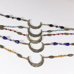 Several ornate crescent headdresses arranged horizontally, comparing bronze and silver tones, different bead sizes and black, red, purple, amber and blue accents.