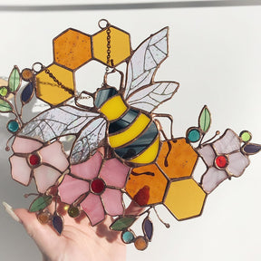 Bee and honeycomb stained glass hanging held in a hand to show the floral bee design.
