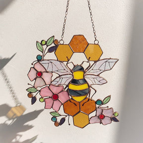 Bee and honeycomb stained glass hanging shown with a bee-shaped shadow on a light wall.