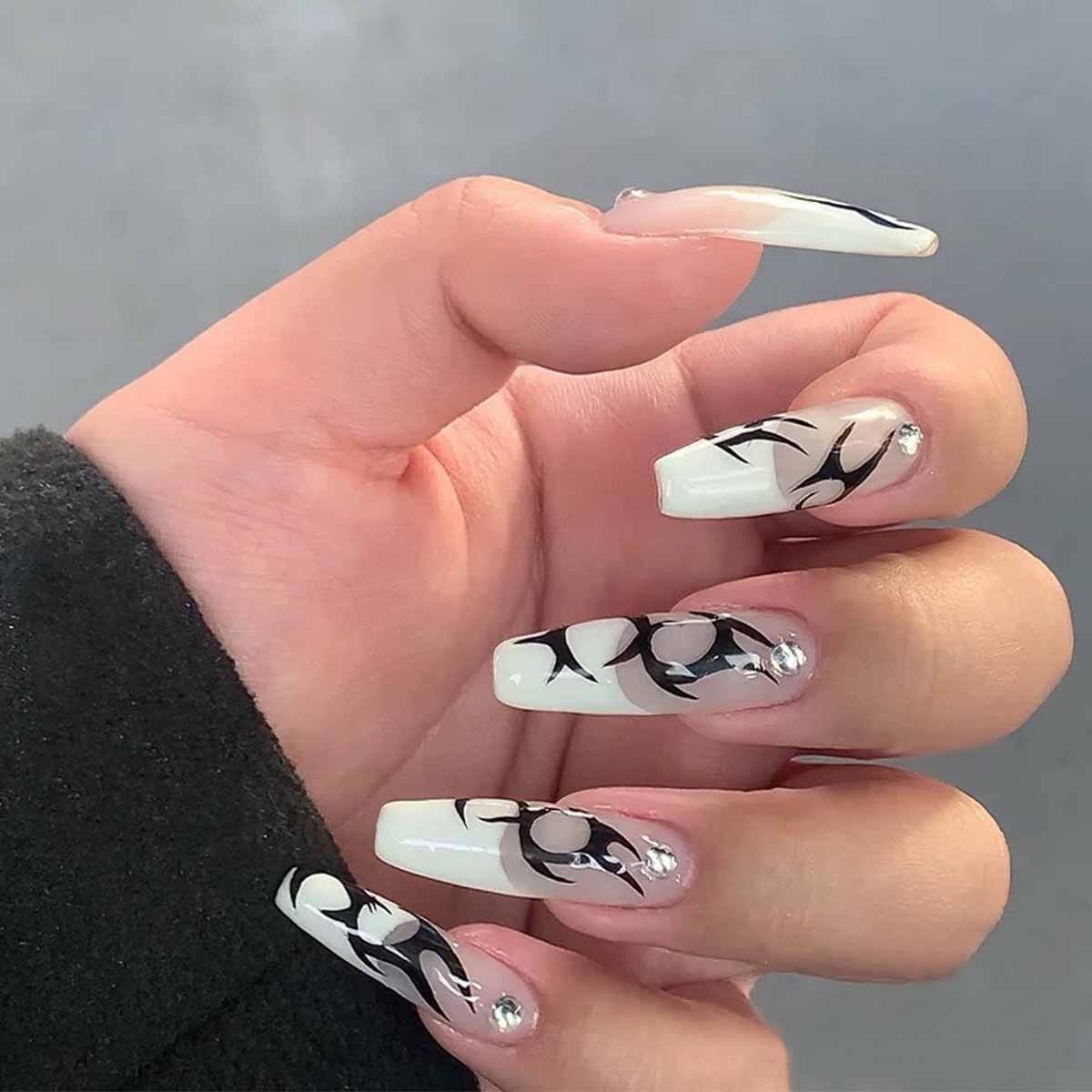 Long square nails with pale French tips, sweeping black abstract curves and individual sparkling cuticle accents over sheer beige bases.
