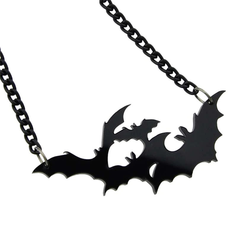 Glossy black acrylic bat pendant shown close up, with overlapping silhouettes and cutout spaces suspended from a black chain.