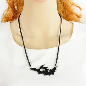 Black bat silhouette necklace worn against a white top to show how the pendant sits across the front.