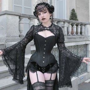 Front view of the black gothic lace overlay beside stone steps, with both sleeves held out to show their ruffled flare.