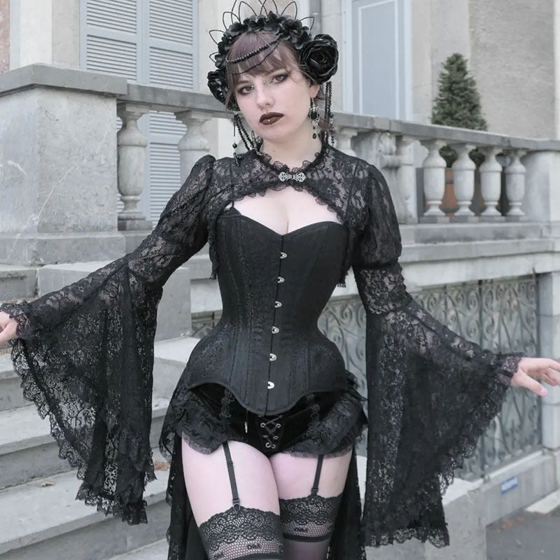 Front view of the black gothic lace overlay beside stone steps, with both sleeves held out to show their ruffled flare.