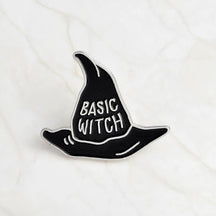 Black Basic Witch pointed-hat enamel pin with silver-tone lettering and a narrow silver-tone border.