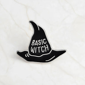 Black Basic Witch pointed-hat enamel pin with silver-tone lettering and a narrow silver-tone border.