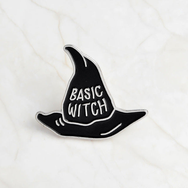 Black Basic Witch pointed-hat enamel pin with silver-tone lettering and a narrow silver-tone border.