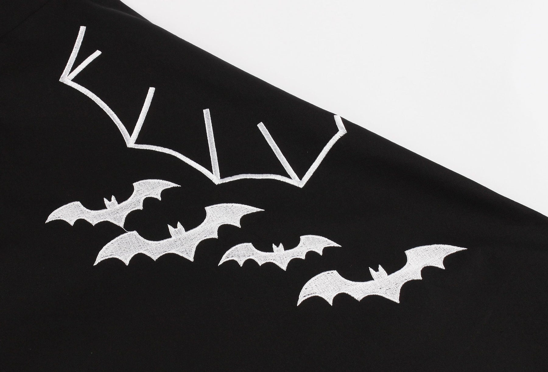 Close-up of white bats and a large outlined wing printed across the front of the black dress skirt.