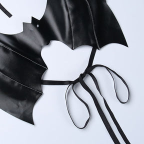 Black bat bralette laid flat to show the curved lower opening, wing stitching and thin straps tied in a bow.